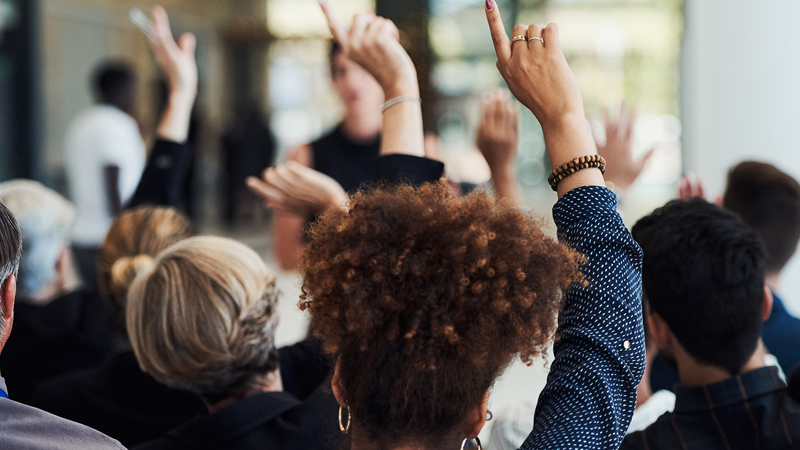 Employees raising hands to ask a question during the First Annual Employee Briefing